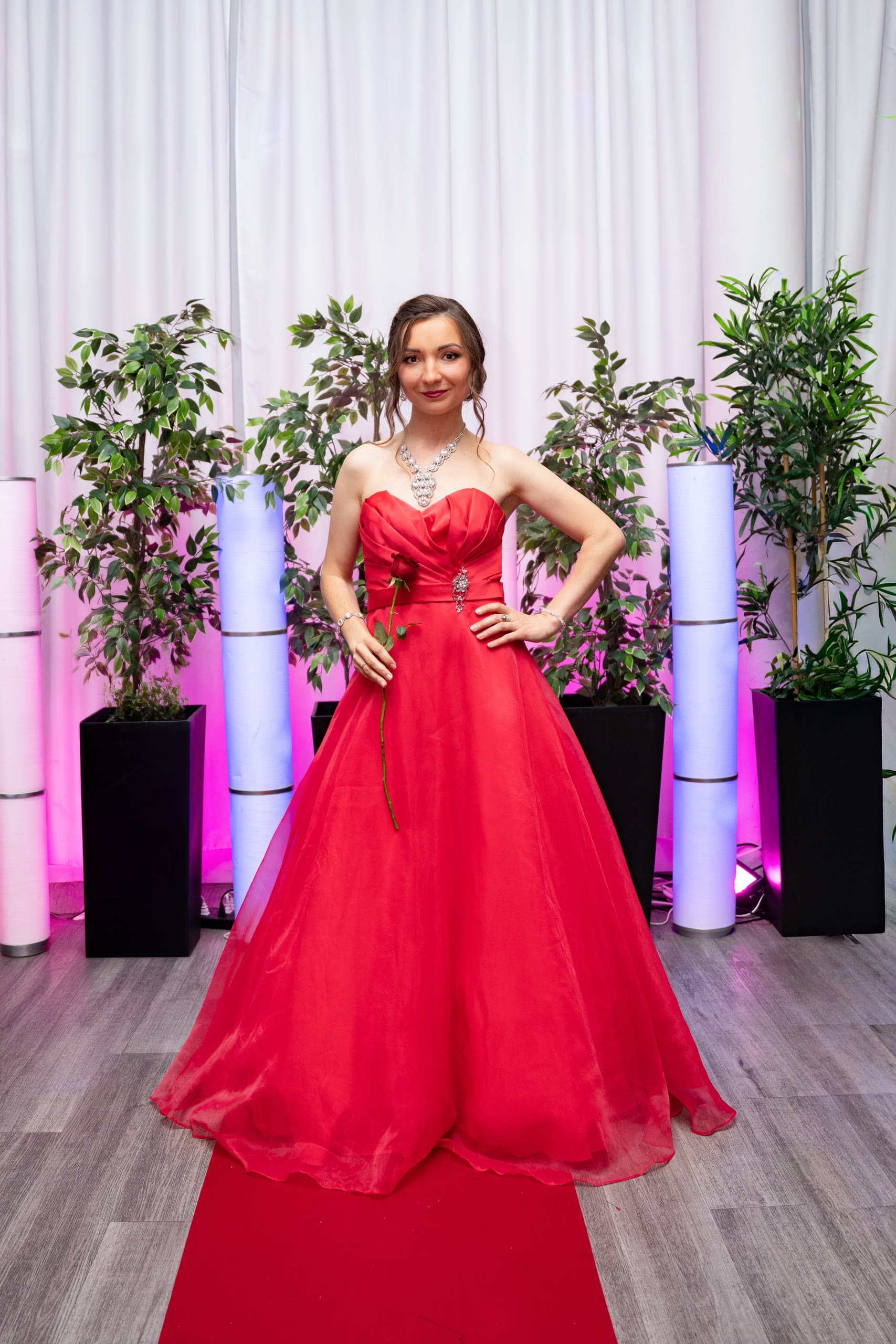 Anastasiia in a red gown under pink stage lights