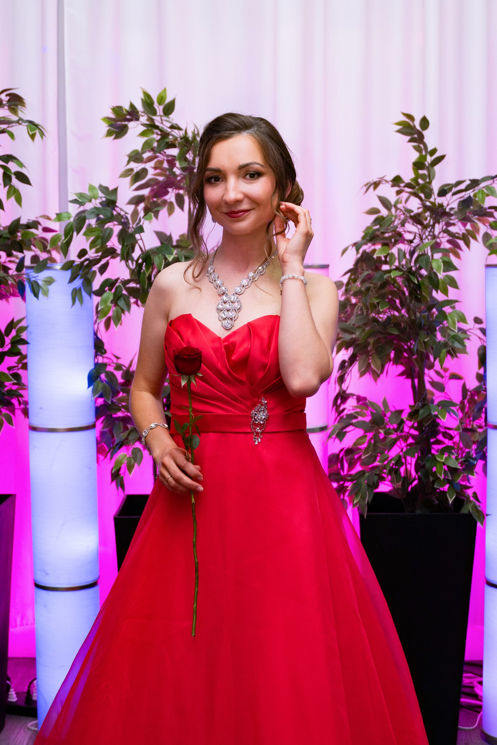 Anastasiia smiling in a red gown, hand raised