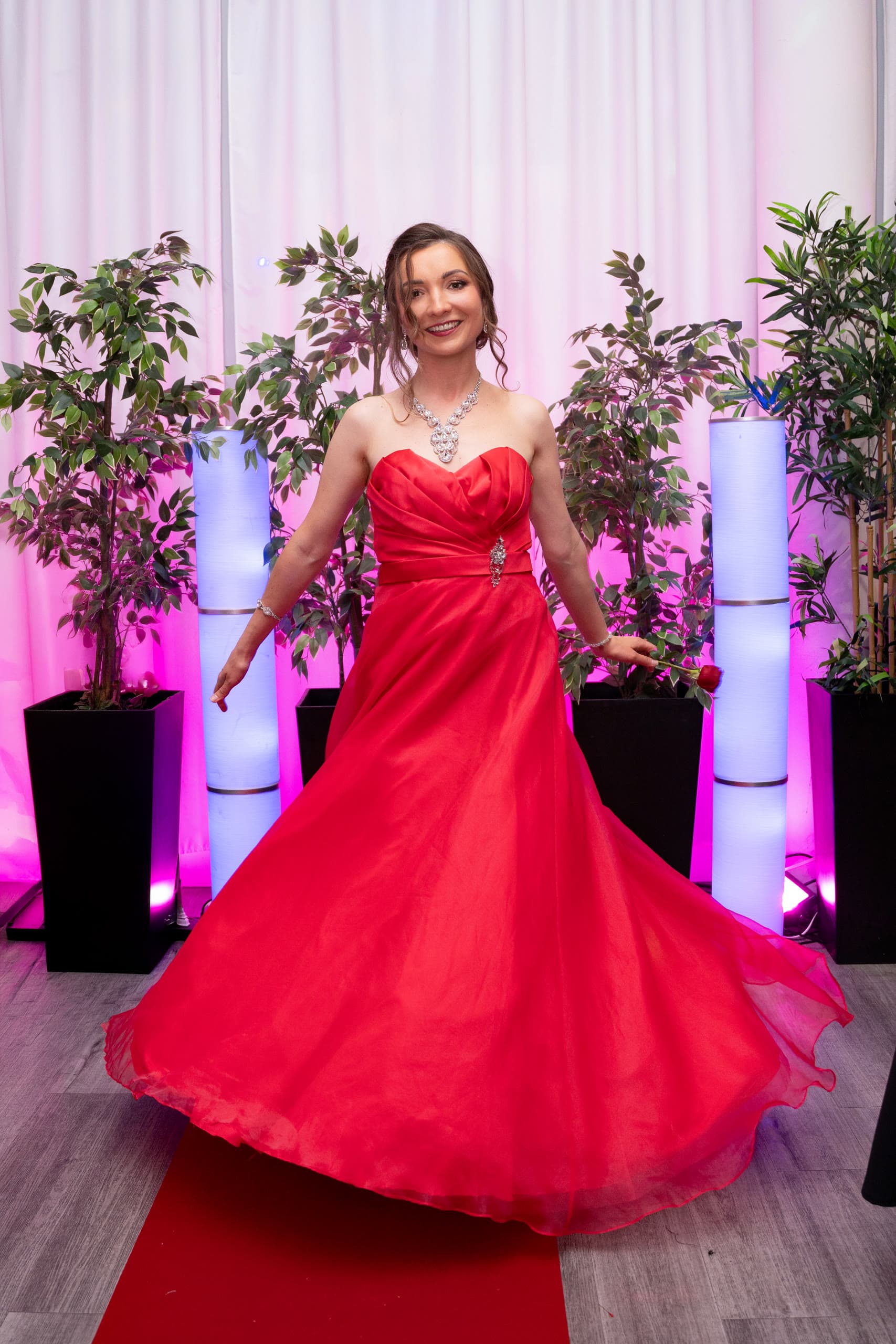 Anastasiia mid-spin, red gown flowing under pink lights